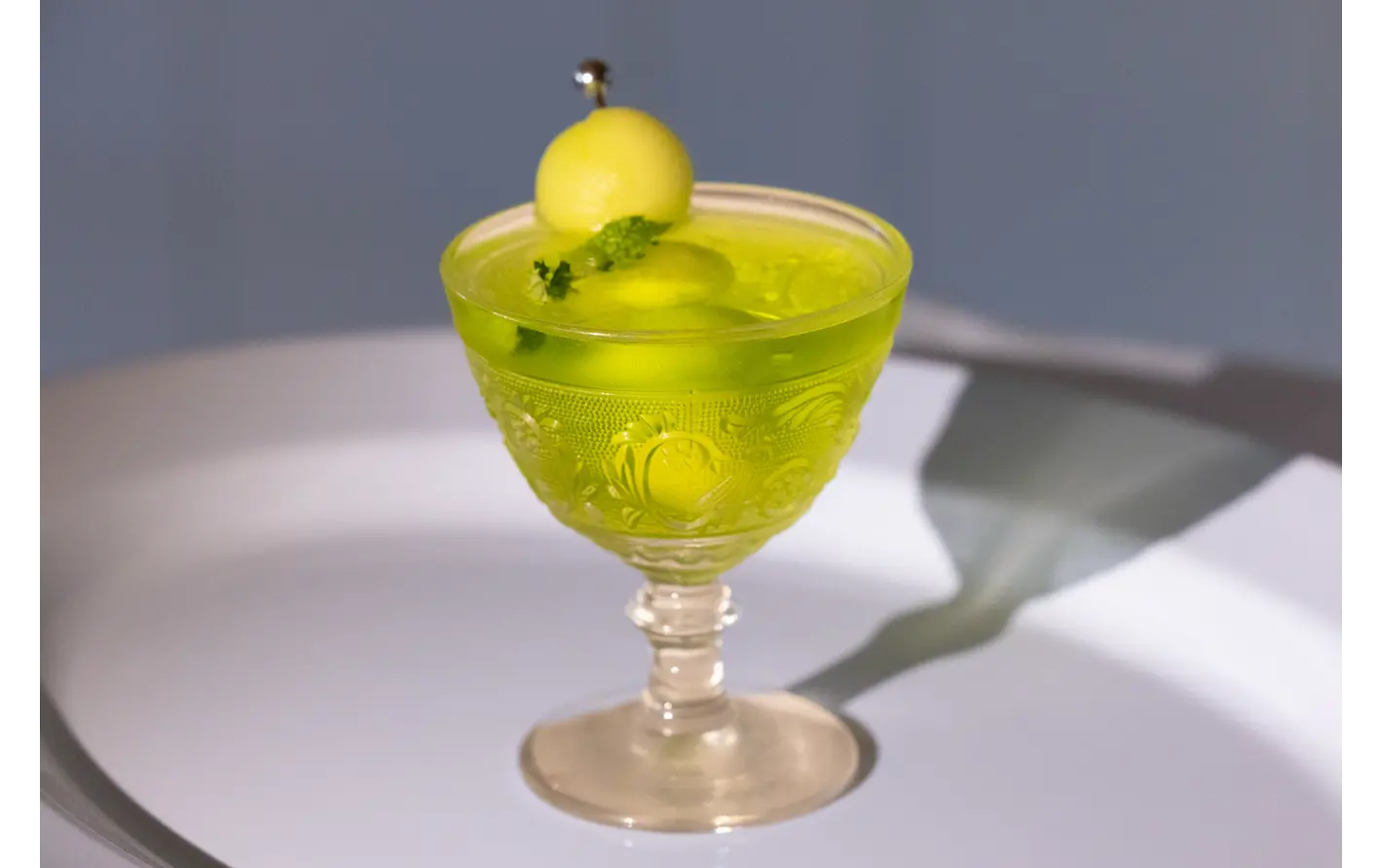 Melon Margarita with Midori and melon ball garnish.